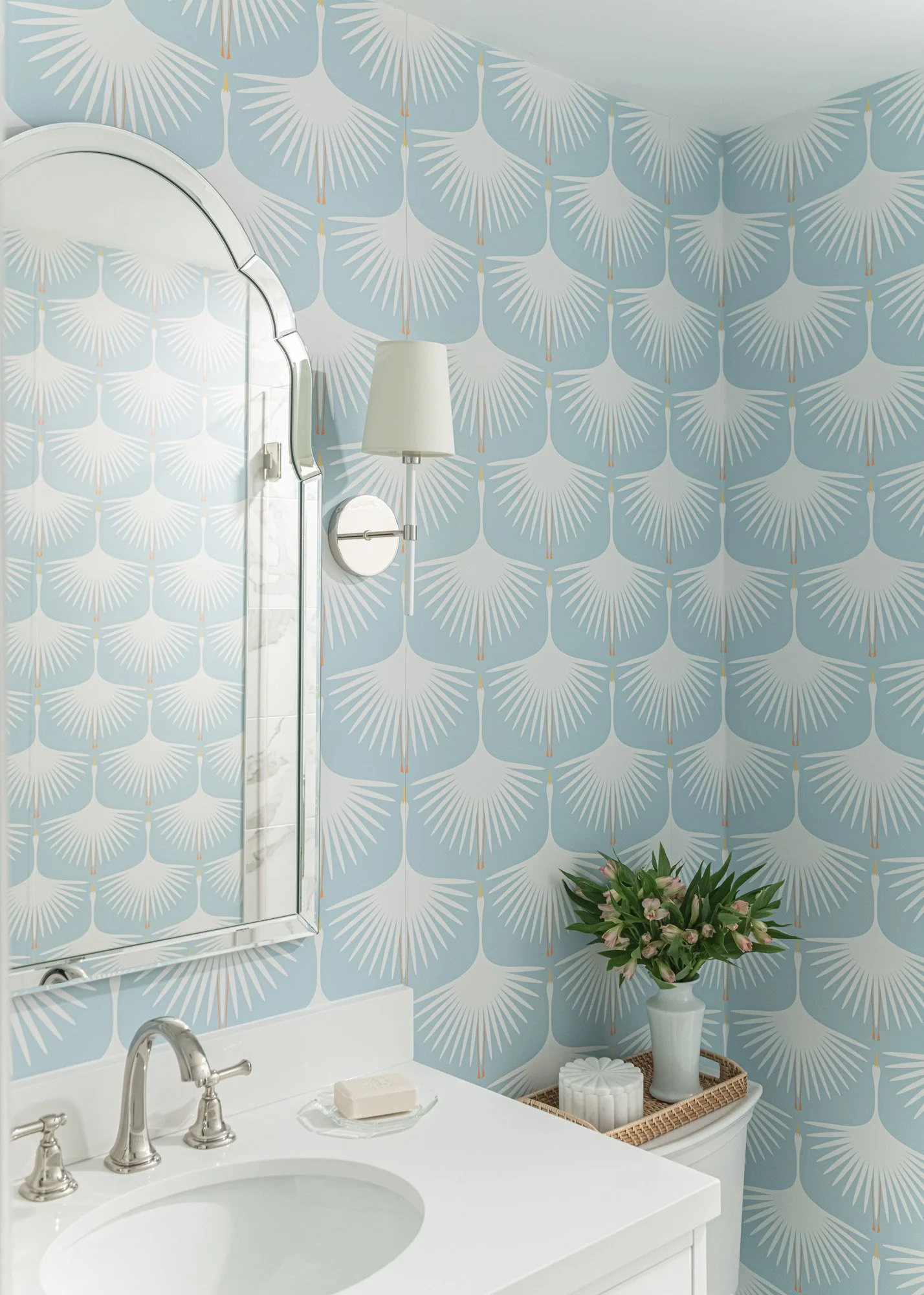 A bathroom with a blue graphic tile floor, marble counter and brass fittings