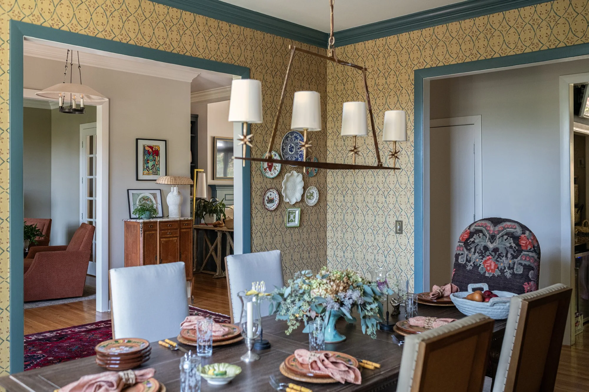 The Woodford Place dining room seen from the entry, with the trellis wallpaper meeting the teal cornice
