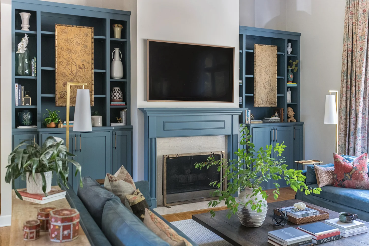 A living room with a soft blue sofa, built-in shelving and a large window