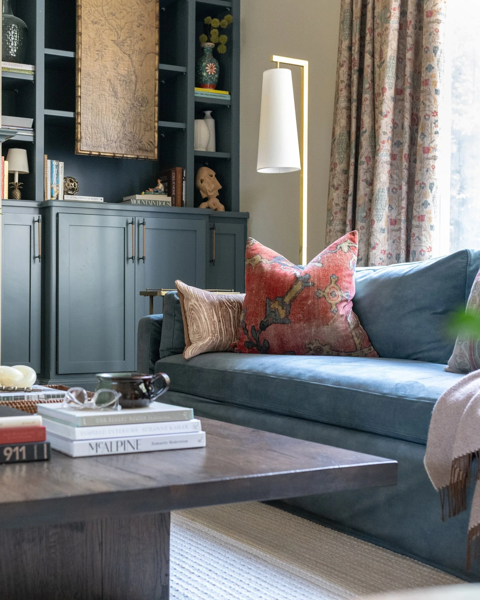 A living room layered with soft blues, warm wood and a patterned rug
