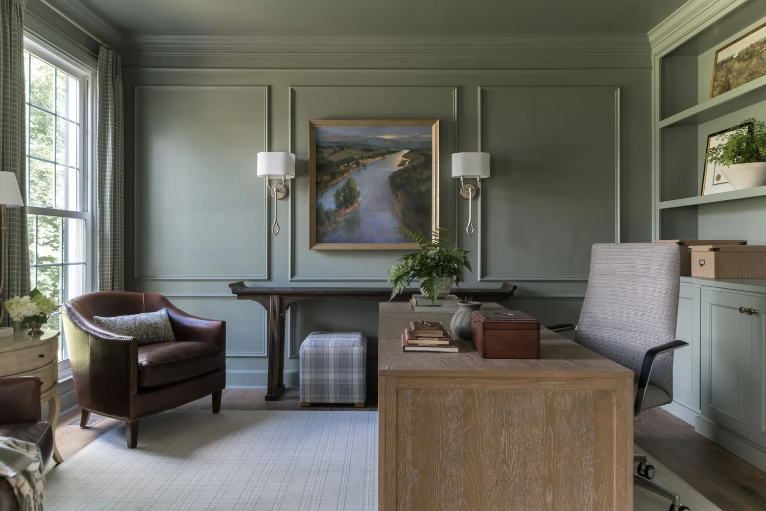 A study with built-in shelving, a wooden desk and a patterned window shade